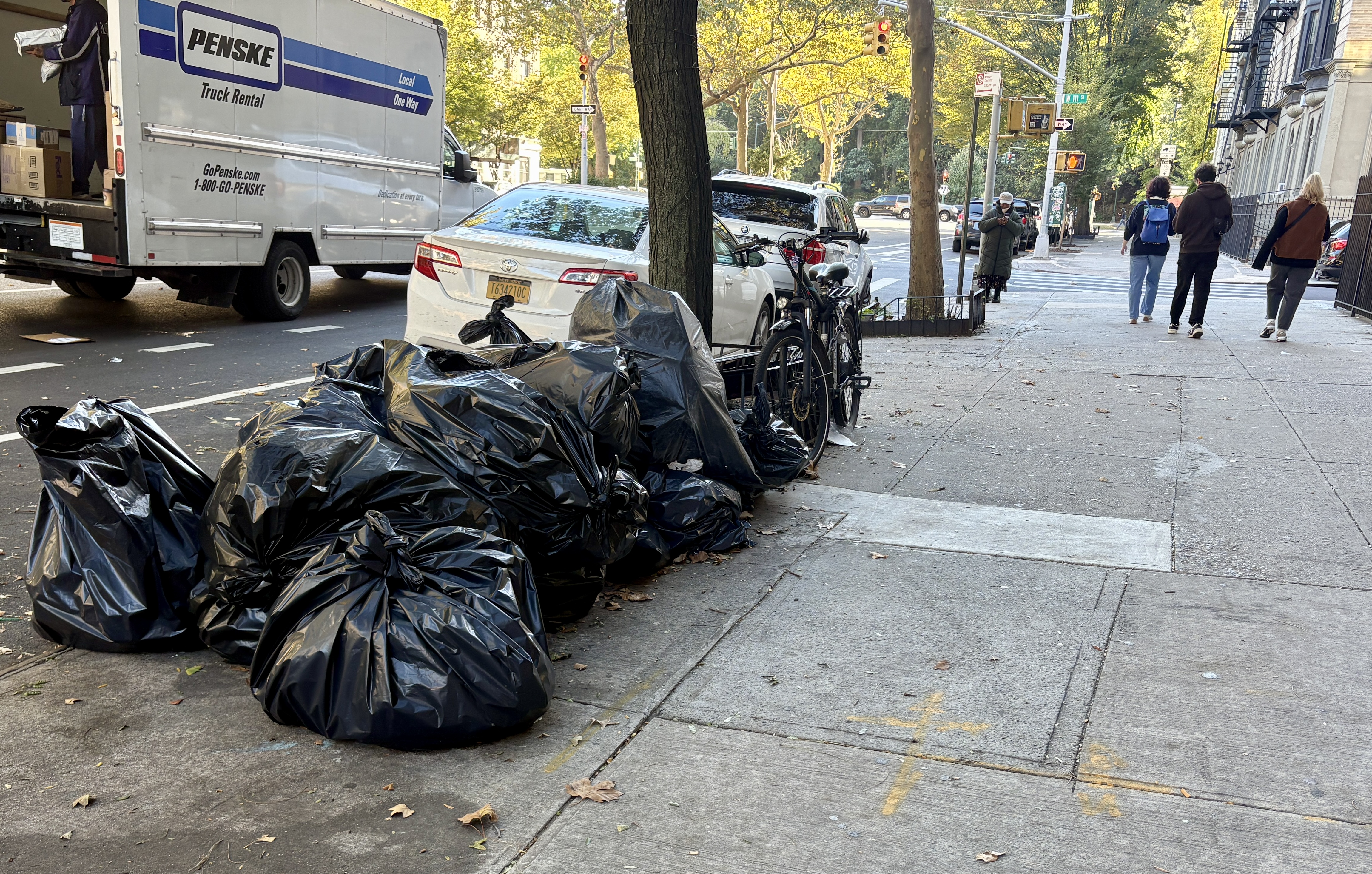Black trash bags lines a street corner in Central Harlem.