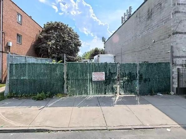 A green, broken fence stands between two buildings in East Flatbush, Brooklyn.